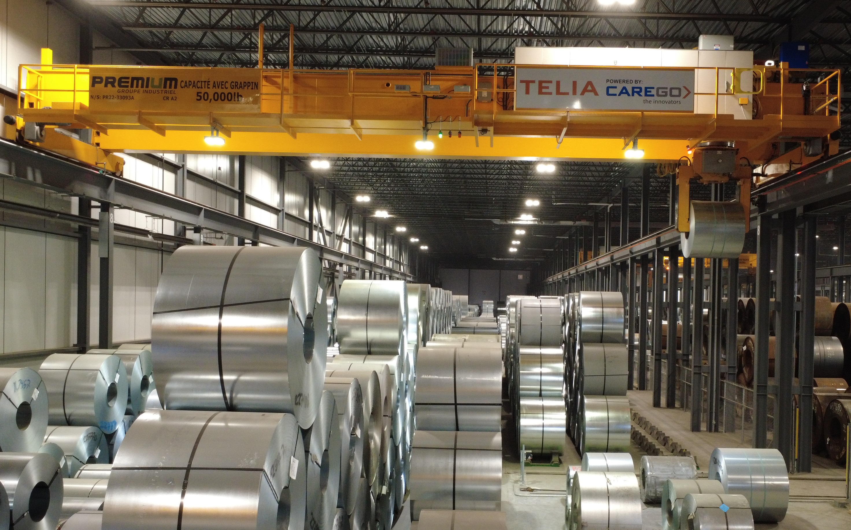 Automated metal service center with TELIA-powered overhead crane handling metal coils